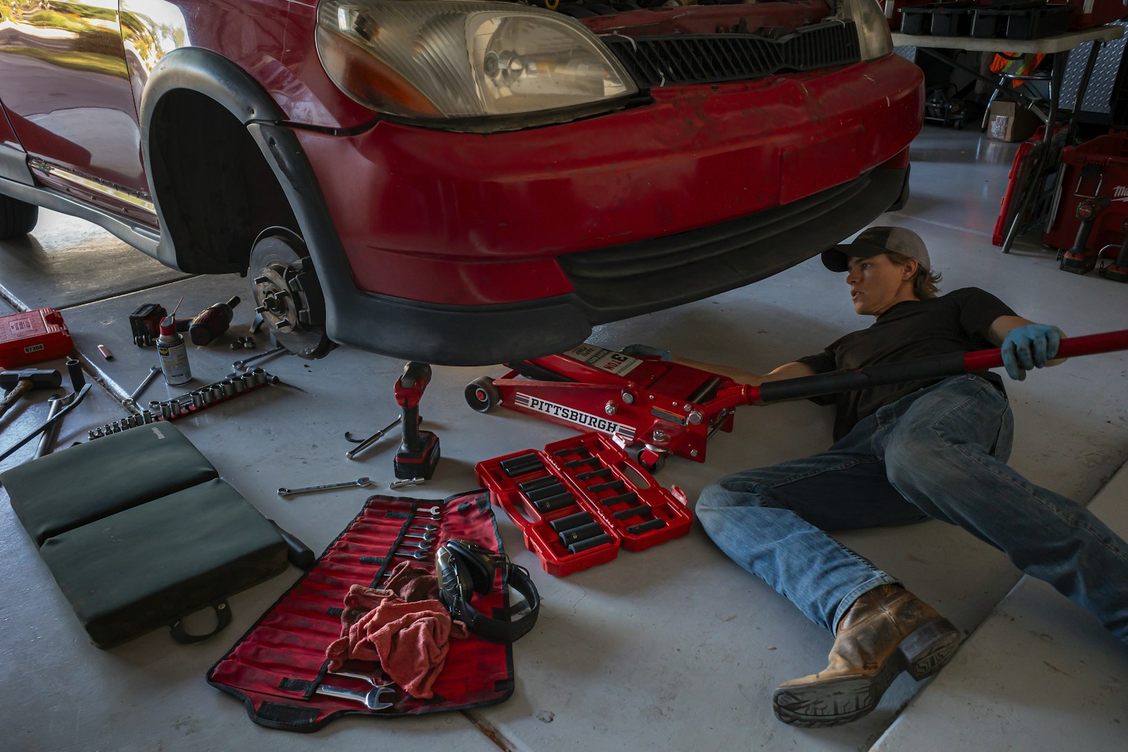 Mechanic working under a car, using a wrench to tighten bolts, performing maintenance in a professional garage